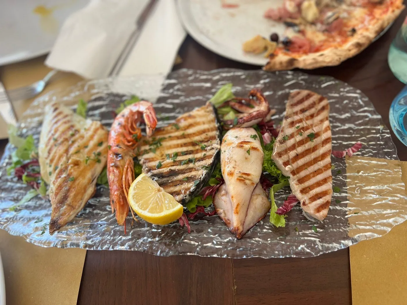 Grigliata mista di pesce servita su piatto di vetro